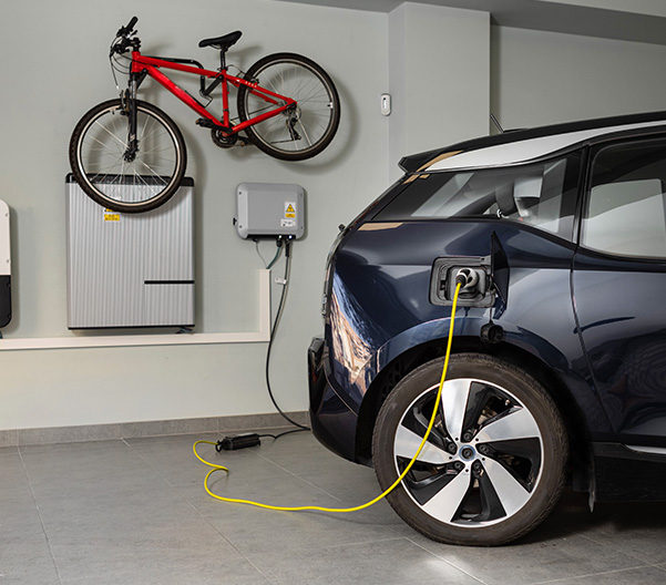 Electric car charging from a wall-mounted home EV charger in a garage