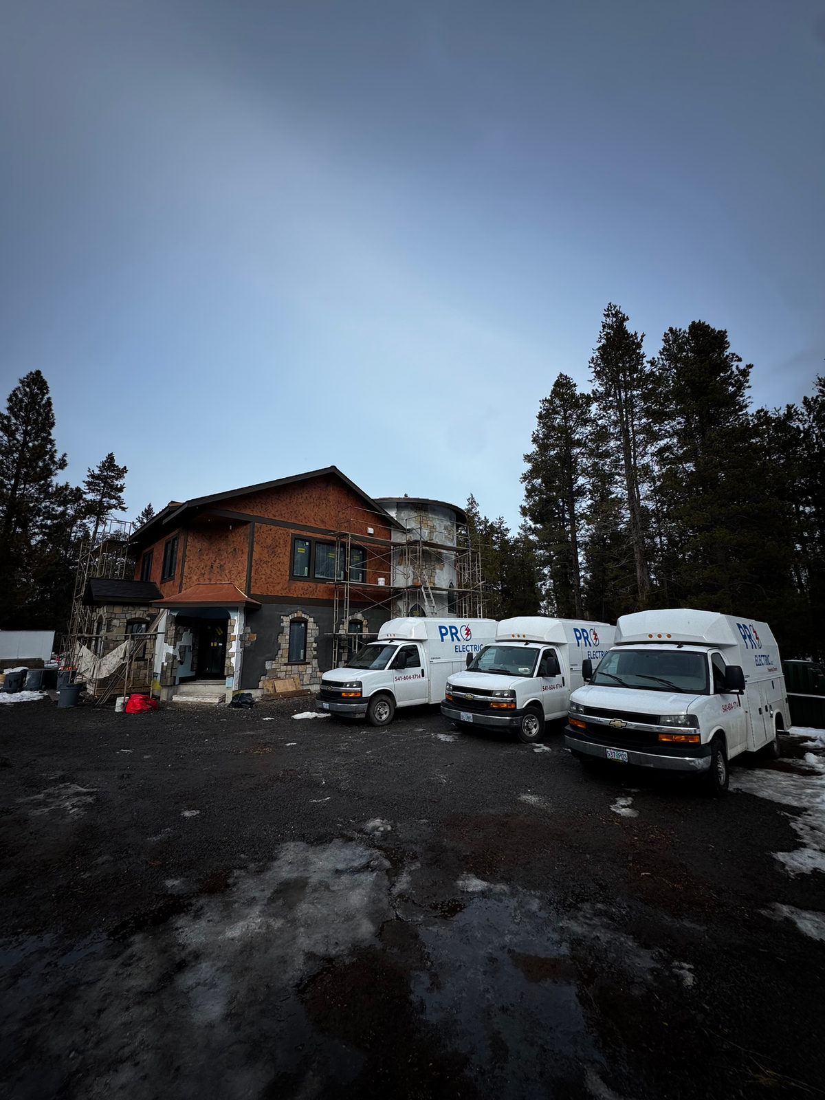 Three Pro Electric service vans parked at a new home build in the pines